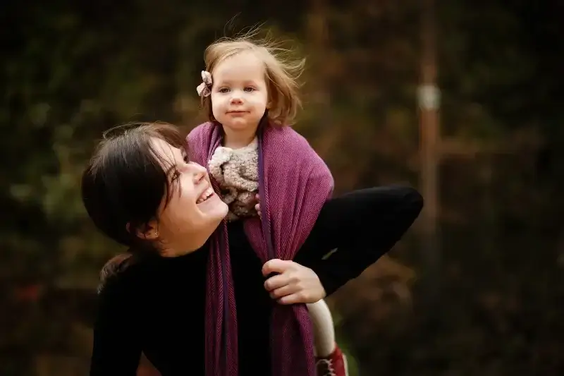 Nauka wiązania chust. Doradca chustowy Paulina Kołodziejska z córką zawiązaną w chuście na plecach