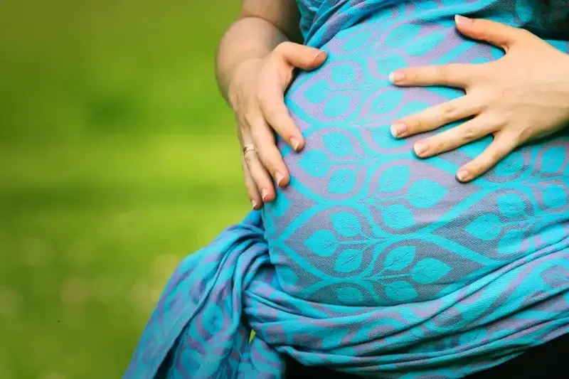 Konsultacja brzuszkowa przed porodem. Kobieta w ciąży owinięta chustą do noszenia dzieci